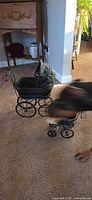 Large and small black wicker doll prams on carpet