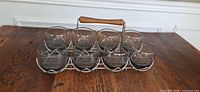 Eight smokey glass tumblers in chrome carrier, view from front