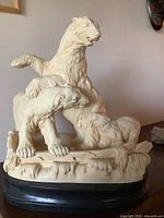 Full view of cream-tone sculpture showing three polar bears on black base