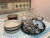 Group shot of all items on counter: glass rolling pin, bowls, mixing bowl, measuring cup, glass stir rod, bag of metal molds