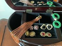 Open Bombay jewelry chest showing compartments, beaded necklace, green hoop earrings, assorted costume earrings