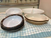 All items laid out: three patterned stoneware bowls stacked, two beige oval stoneware bakers, one translucent plastic mixing bowl with lid, one white plastic divided serving bowl with lid