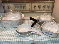 Group shot of all five Corning Ware pieces with lids and handle visible