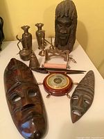 All items laid out together showing brass pieces, wood carvings, barometer, roller press and letter opener