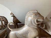 Close-up of cast metal lion supporting frosted glass bowl