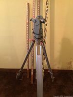Tripod with transit and four leveling rods front view