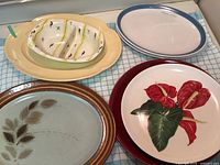 Five ceramic plates and bowls displayed on cloth