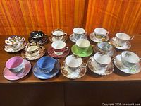Group shot of all sixteen teacup and saucer sets on table