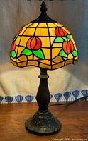 Lamp illuminated showing stained glass pattern and metal base