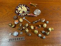 Full assortment of Toronto Fire Department pins, buttons, tie clips and insignia laid out on wood surface