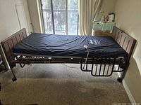 Full view of assembled hospital bed showing mattress, frame, headboard, footboard, side rail and hand controller
