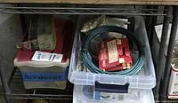 Shelf with bins showing picture wire coil, D-ring package, boxed hardware, labeled Allen wrenches container