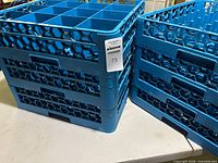 Two stacks of blue plastic glass racks, showing honeycomb sides and MaxSold tag