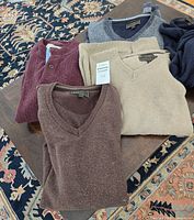 Stack of burgundy, beige, brown, gray sweaters on table