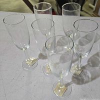 Six plain clear glass champagne flutes on tabletop