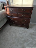 Front view of nightstand showing six drawers and brass handles