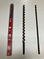 Three bits laid out: packaged Milwaukee ship auger, rusted auger, rusted twist drill