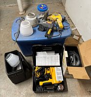 Overview of sprayers, paint cups, accessories on blue tote and floor