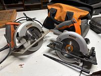 Both Ridgid circular saws on table with soft tool bag