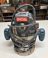 Front view of Ryobi RE180PL router showing logo, handles, power cord and 2 HP rating