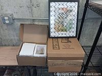 Boxes containing multiple black picture frames, one frame displayed upright