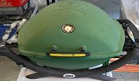 Closed green Weber portable grill showing lid thermometer and handles