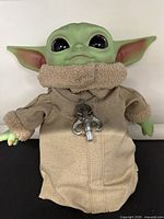 Front view of 12" Grogu plush wearing tan robe and pendant