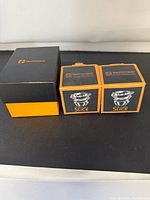 Three Nachtmann boxes: one large black/orange box for Skull tumbler, two smaller Slice votive holder boxes