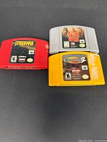 Front view of three Nintendo 64 cartridges: Spiderman red, WCW Nitro grey, Tony Hawk's Pro Skater 2 yellow