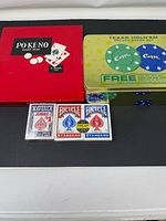 Lot overview showing Po-Ke-No box, Texas Hold’em tin, three playing card decks