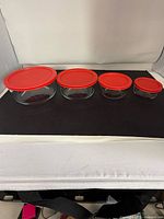 All four glass bowls with red lids in size order