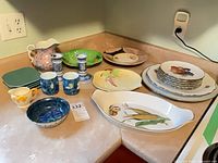 Assorted plates, cups, candlesticks and creamer on countertop