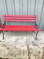 Front view of red slat bench against siding