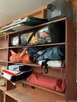 Shelf with Coleman tent bag, tarps, water container, folded frame