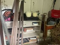 Shelf area showing planters, stakes, shovel, seeder, pots, duct pieces