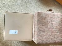 Cube stool with lid removed and cushion beside