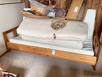 Front view of wooden futon frame with mattress folded on seat