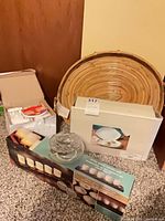 Group shot of all boxed items including rattan tray, candle set, serving dishes, coasters box and glass potpourri bowl