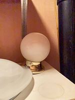Brass-base white glass globe fixture beside part of frosted dome shade