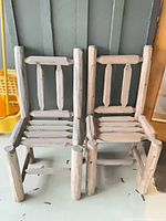 Two log chairs side by side against wall