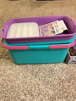 Closed teal sewing tote with purple lid shown on carpet