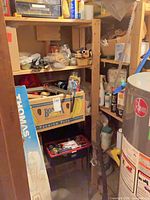 Wide view of shelving unit with toolbox, banana box, axe, hardware