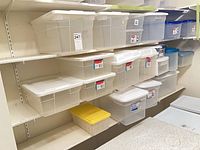 Shelving unit holding multiple clear totes with various colored lids