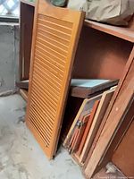 Shutter, stacked cabinet doors and panels visible