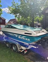 Port stern view showing teal cover, Mariah graphics, and tandem trailer