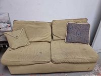 Front view of beige two-seat sofa bed with two throw pillows