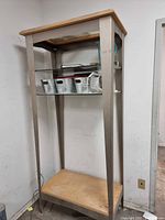 Full view of tall glass, metal and wood shelving unit