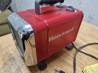 Side view showing Honeywell branding, red housing, handle and feet