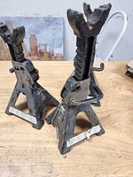 Three black steel jack stands on workbench