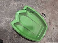 Top view of green plastic sled showing seat, grip ridges, pull rope